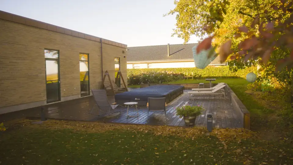 Træterrasse med stole og pool i efterårshave