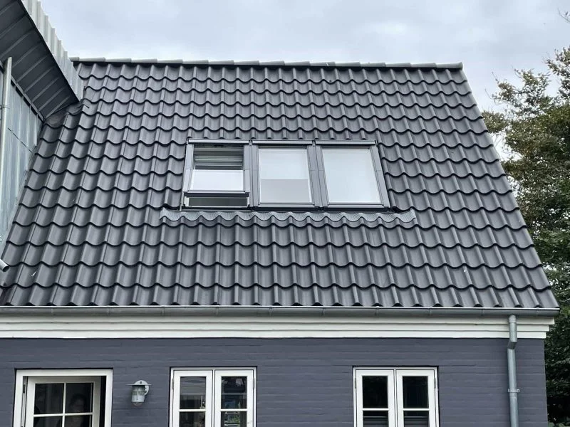 Hus med gråt tegltag og ovenlysvinduer