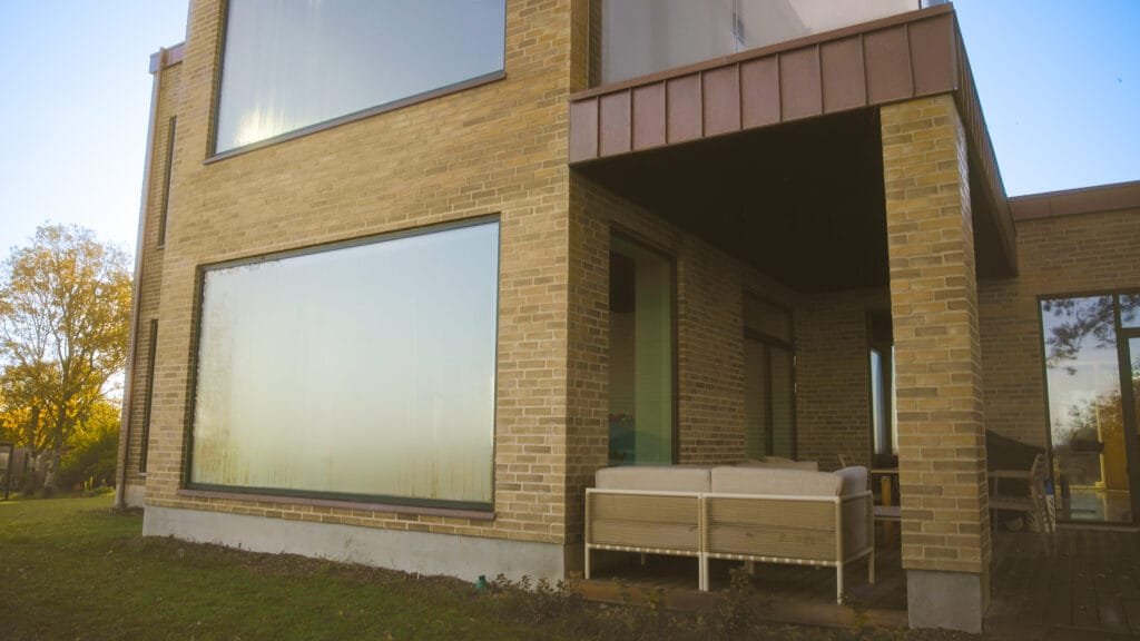 Moderne murstenshus med store vinduer og terrasse