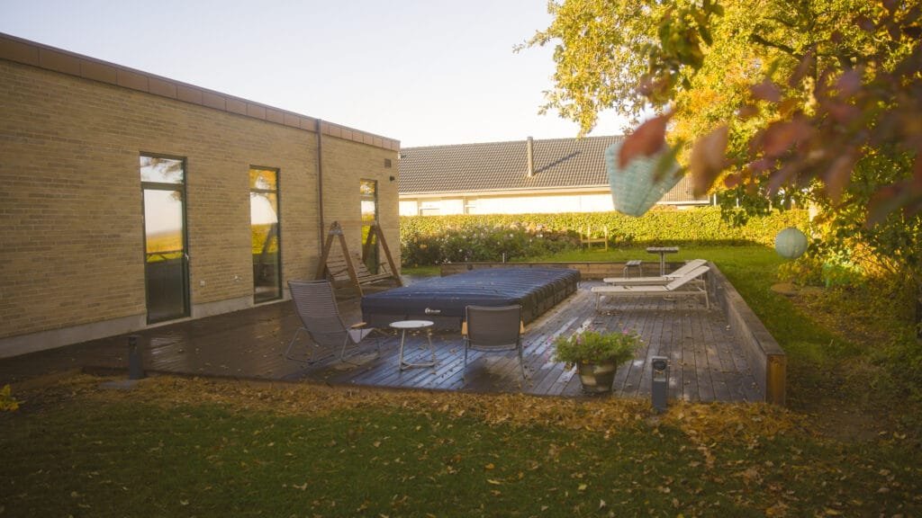 Træterrasse med stole og pool i efterårshave