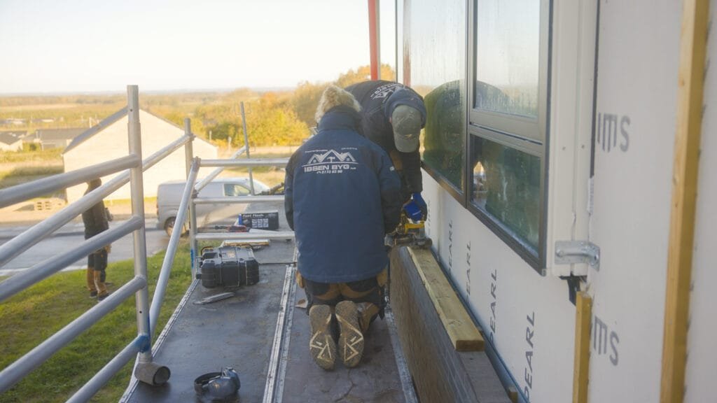 Håndværkere arbejder på facadeisolering af hus