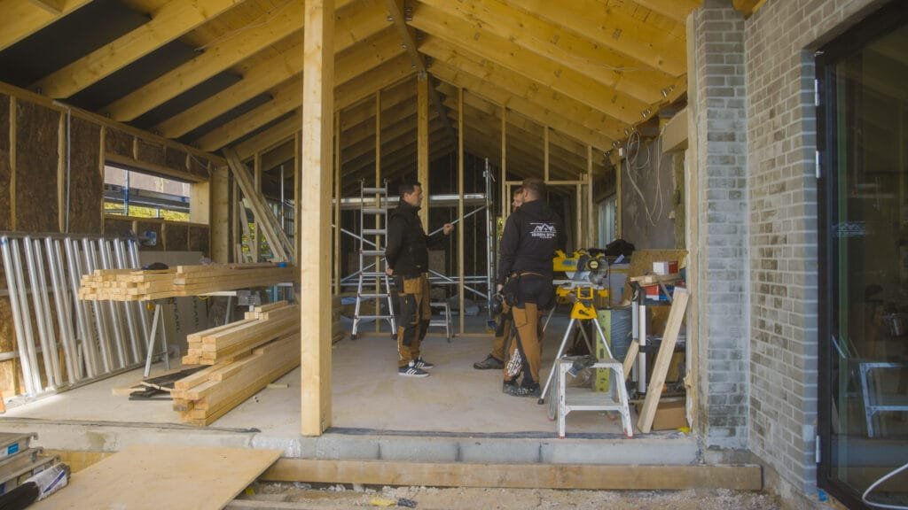 Bygningsarbejdere arbejder på træhus under opførelse